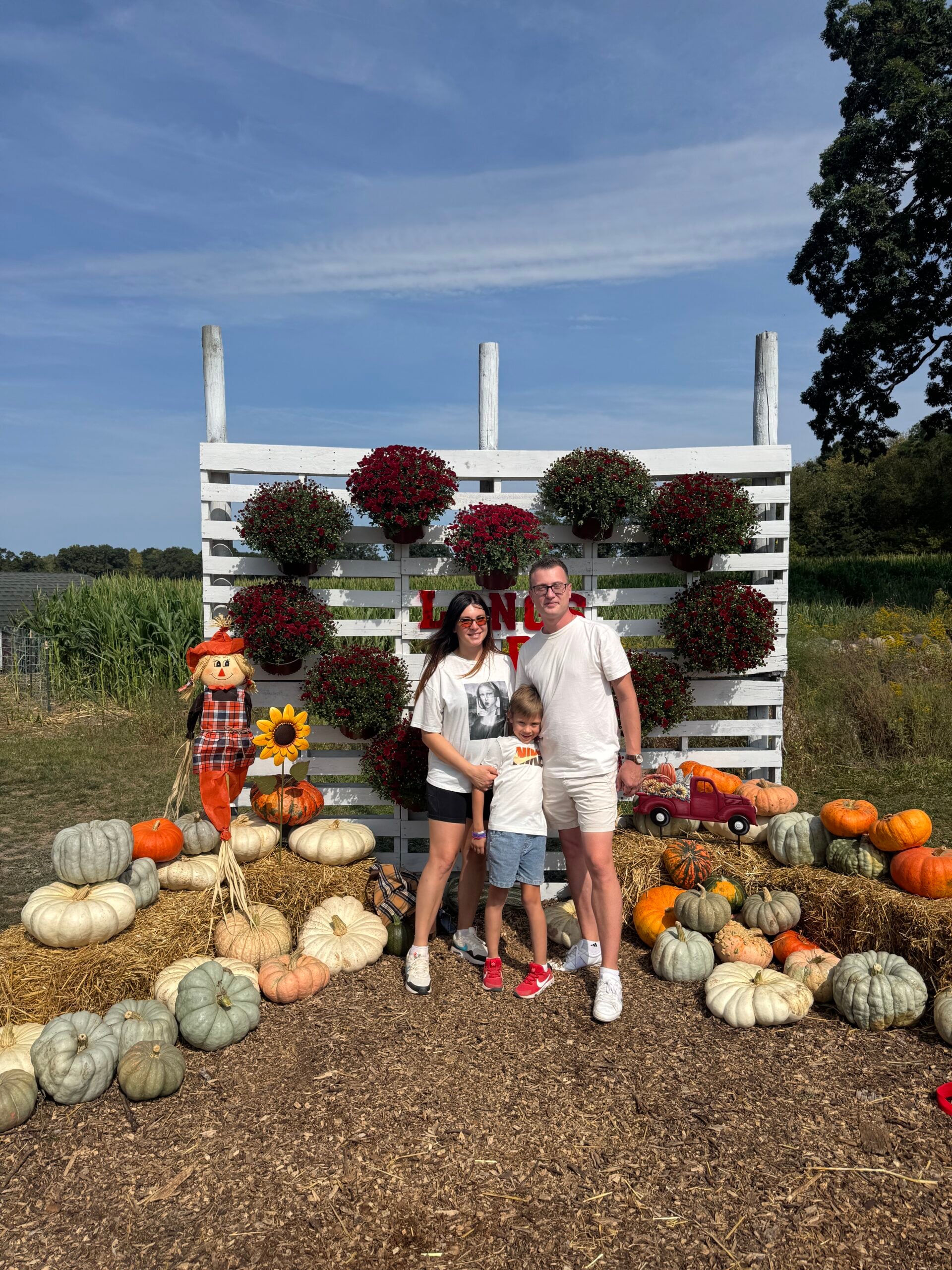 A family posing at the Long's fall photo op with mums and pumpkins