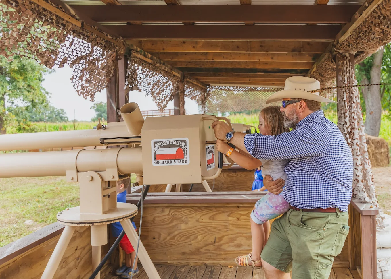 A dad helping his daughter fire the apple cannon